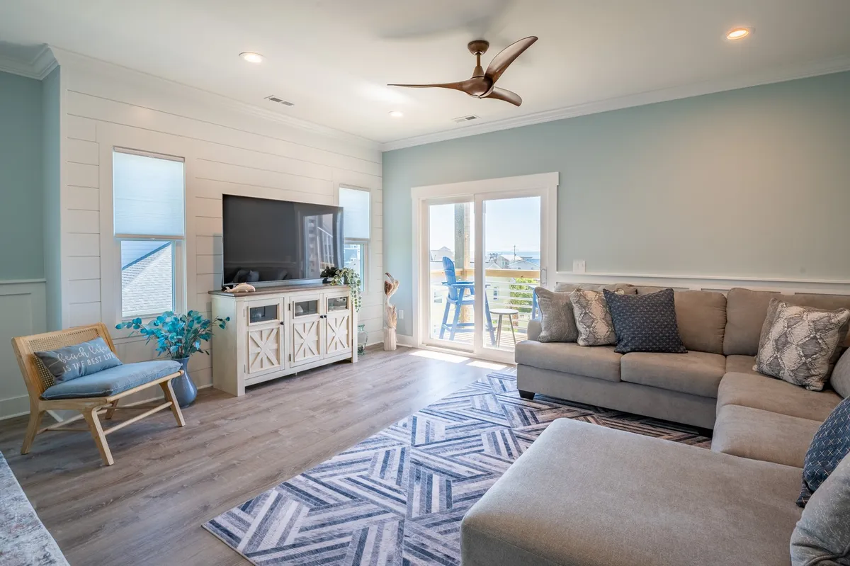 A welcoming living room with a sofa, television, coffee table, rug, and a sliding door that opens to an outdoor view. The space feels inviting for socializing or unwinding, and the sliding door visually connects the interior to the outside environment.
