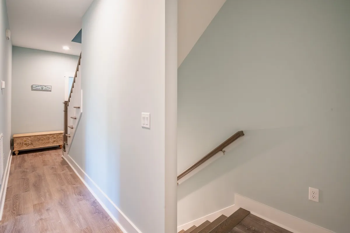 A calm and inviting space with a staircase, a simple bench, and a light blue wall. The scene evokes the feeling of arrival and transition, making a great first impression for guests entering the home.