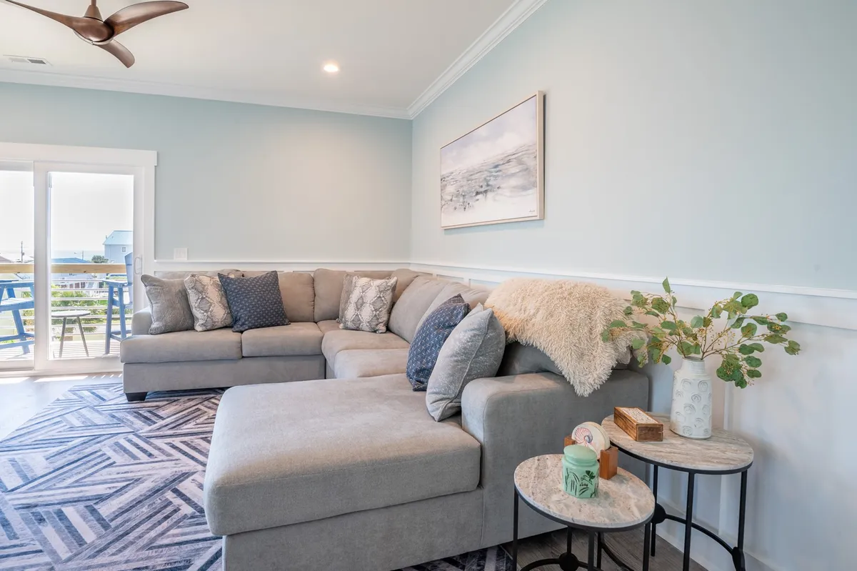 This image showcases a comfortable, cozy living space with a sectional sofa, decorative pillows, coffee table, and wall art. The room is bright and inviting, ideal for family gatherings or relaxing after a day exploring the island.